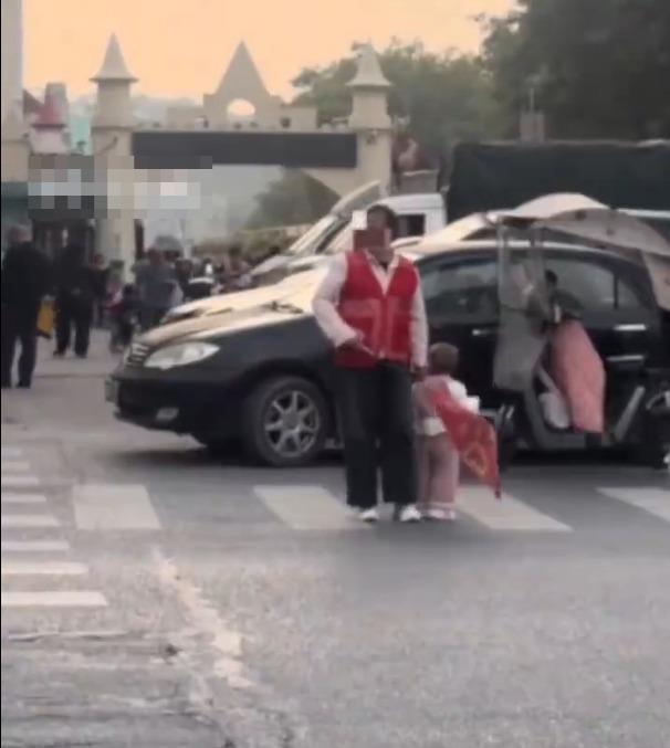 深圳一名幼儿园家长带幼儿在马路上值护学岗怕孩子乱跑紧拽其衣领教育局工作人员：正核实按要求是自愿报名(图1)
